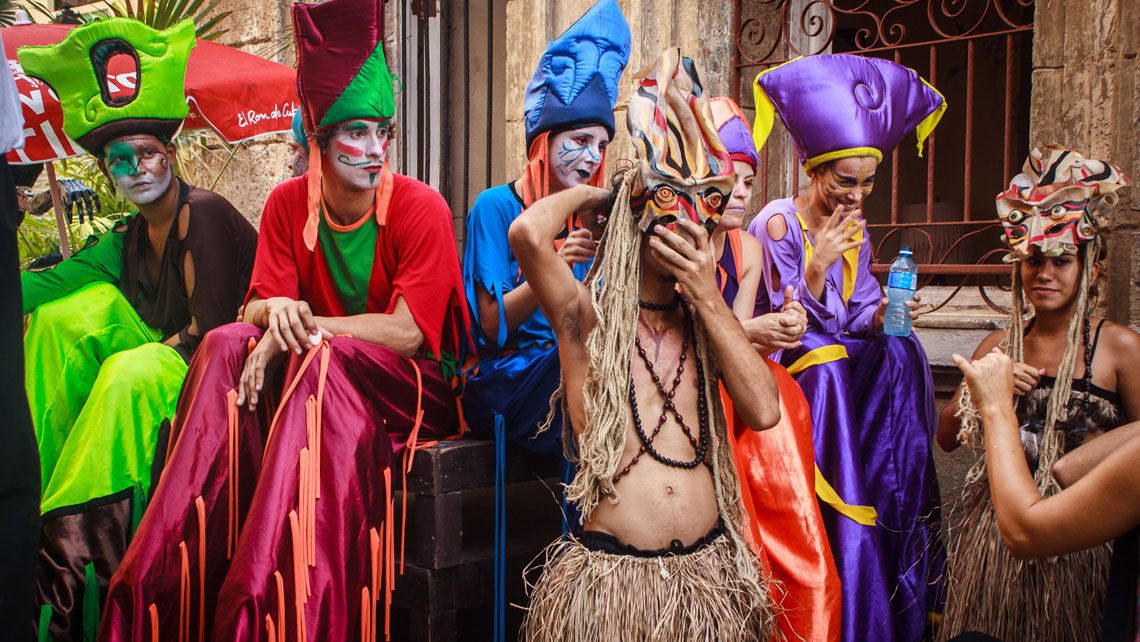 A group of street performers dressed in colorful costumes hanging out in a street of Old Havana