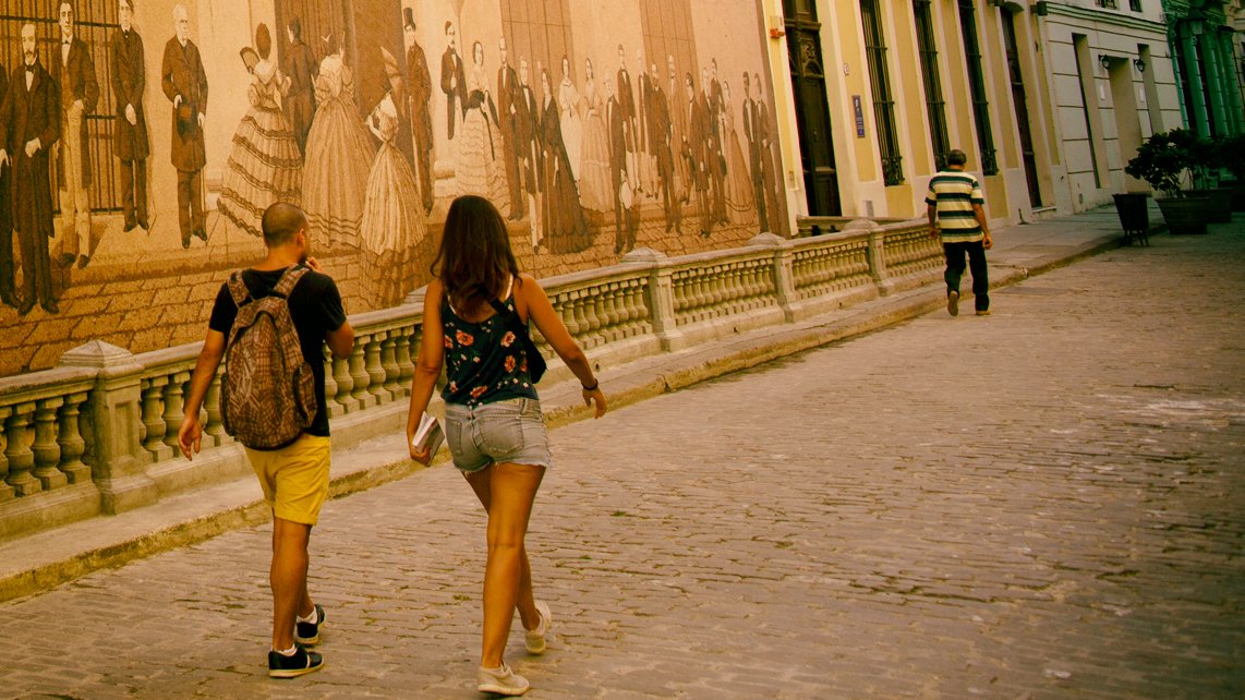 People walking by mural on Mercaderes street, Havana