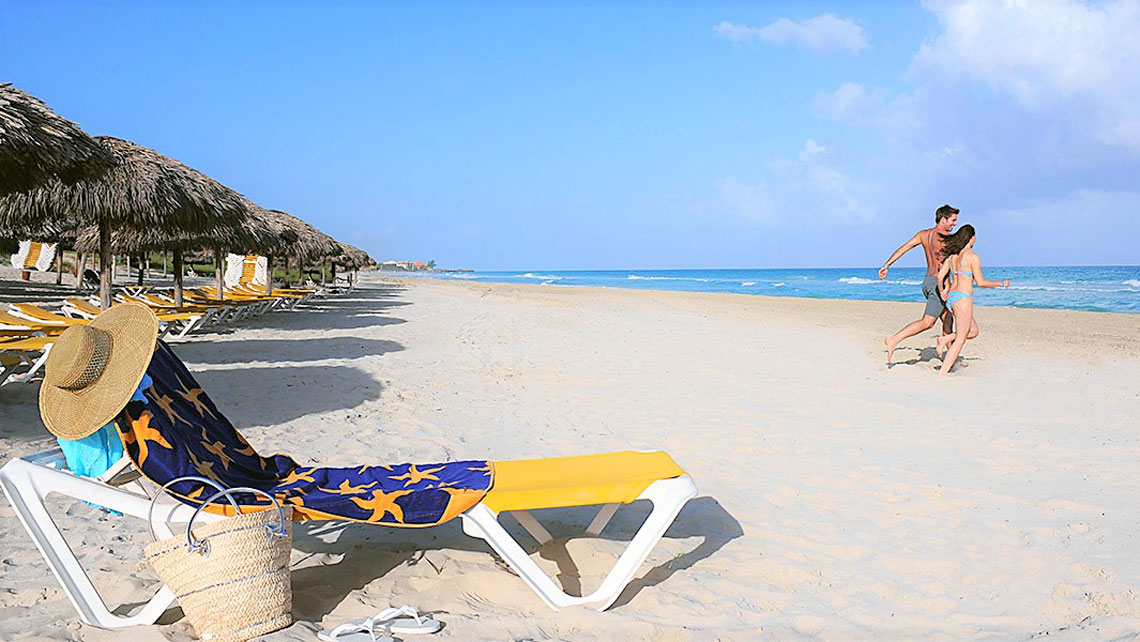 A couple running towards the water in a sandy beach
