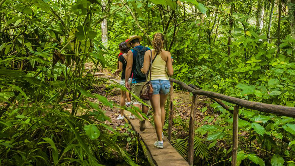 People walking across a rustic bridge on their way to El Nicho waterfalls
