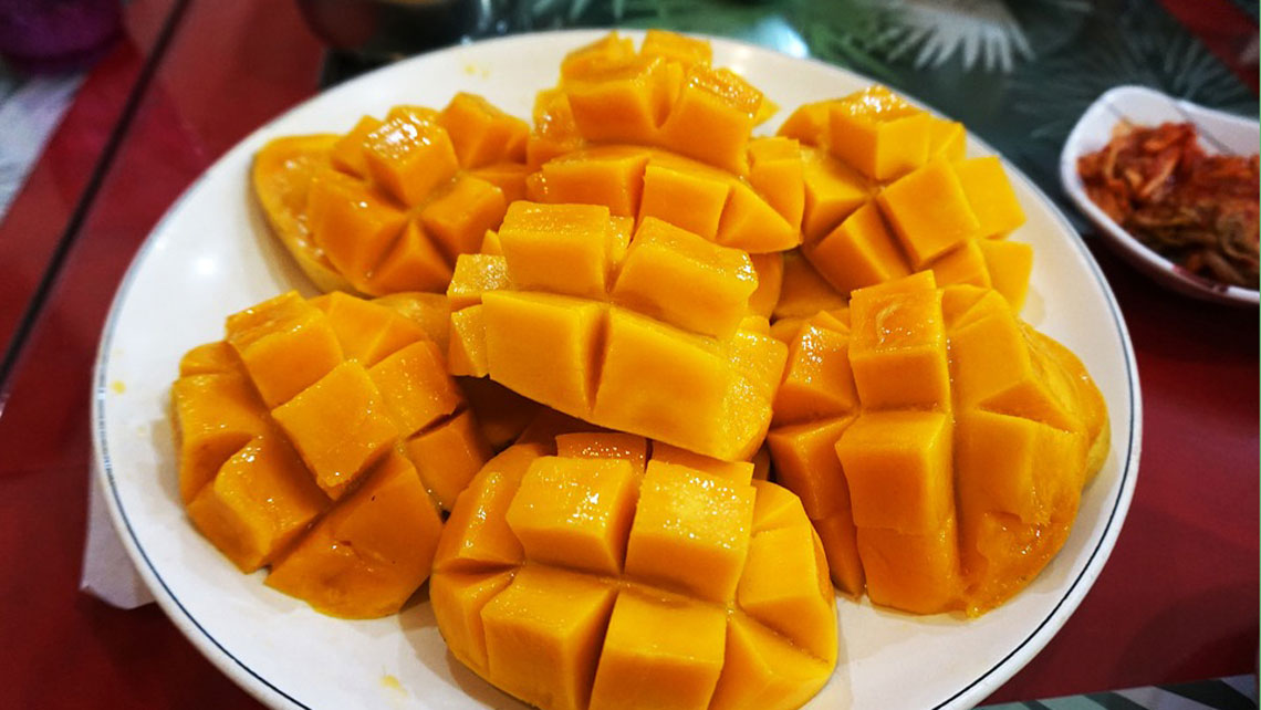 Sliced mango in square pattern in a white plate