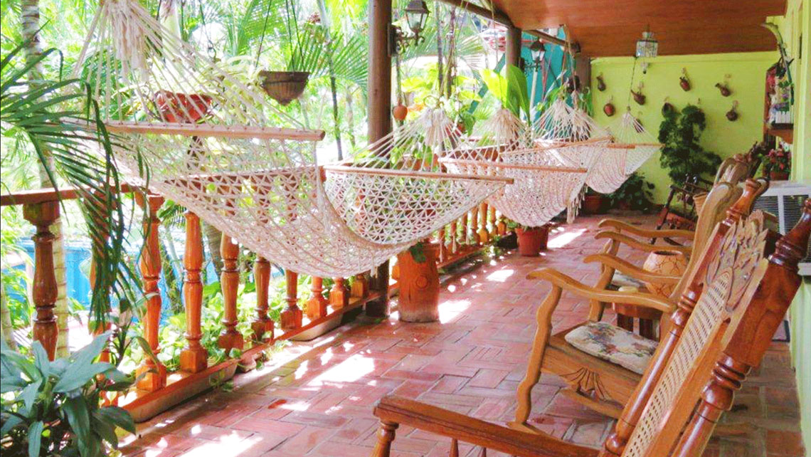 Wooden rocking chairs near hammocks in a veranda of a casa particular