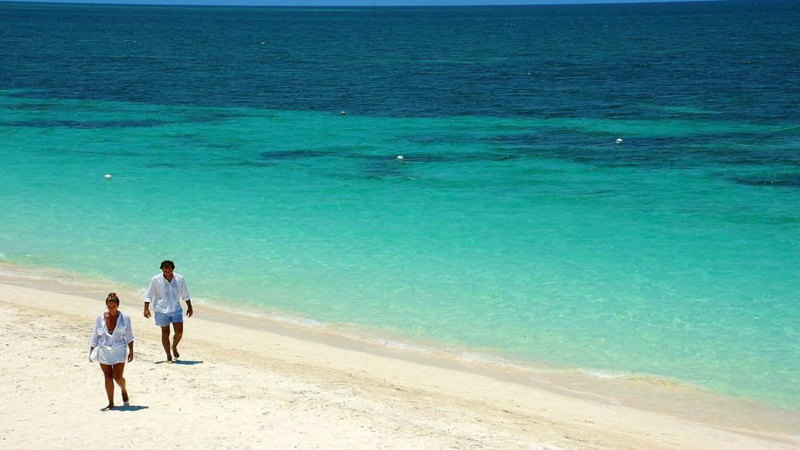 Tourist couple walking on powdery sands