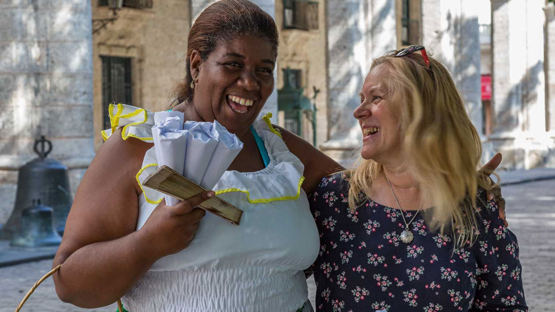 A tourist and a local woman laughing together