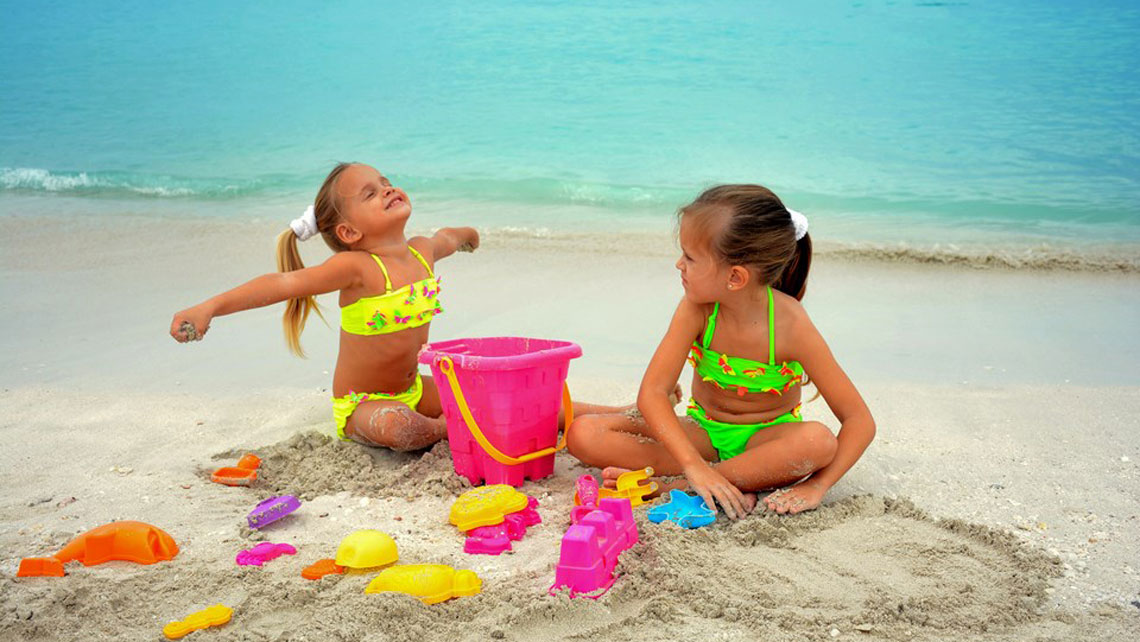Two young girls playing with sand on the beach