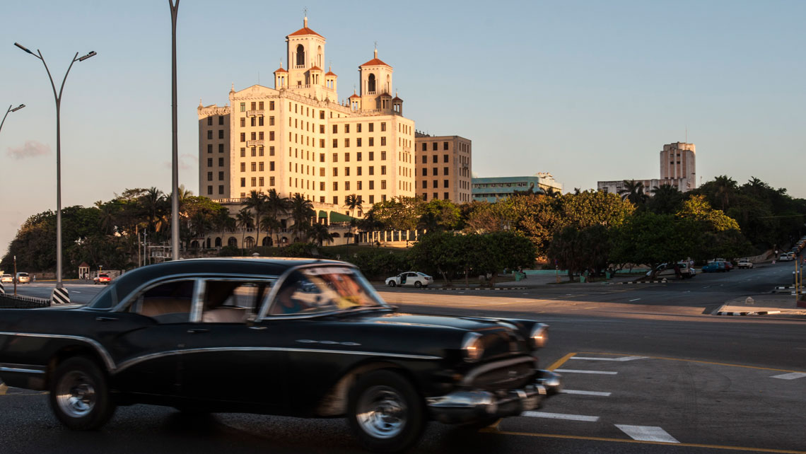 Vintage car cruising on Malecon waterfront in front of Hotel Nacional in Havana