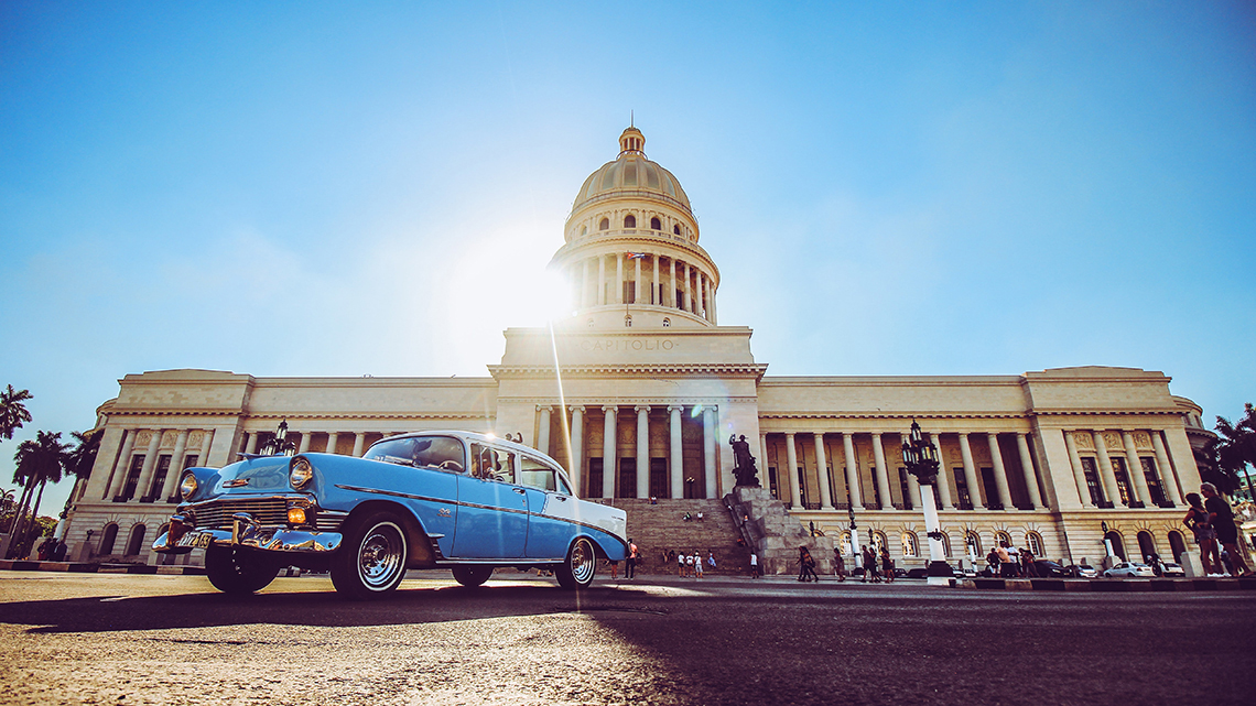 Vintage american car parked in front of the Capitol Building in Havana