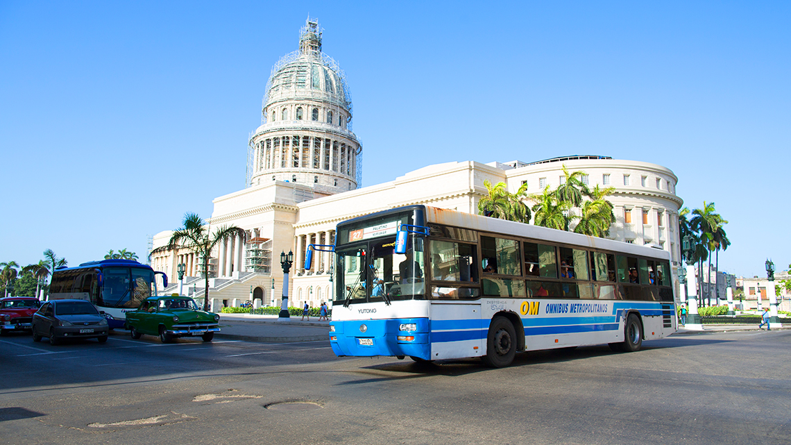 Public bus cruising the streets of Old Havana, in the background Havana's Capitol Building