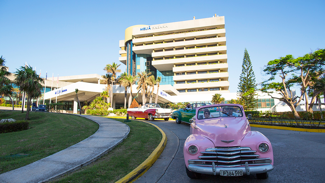Vintage american car beloging to Gran Car leaving hotel Melia Habana with tourist onboard