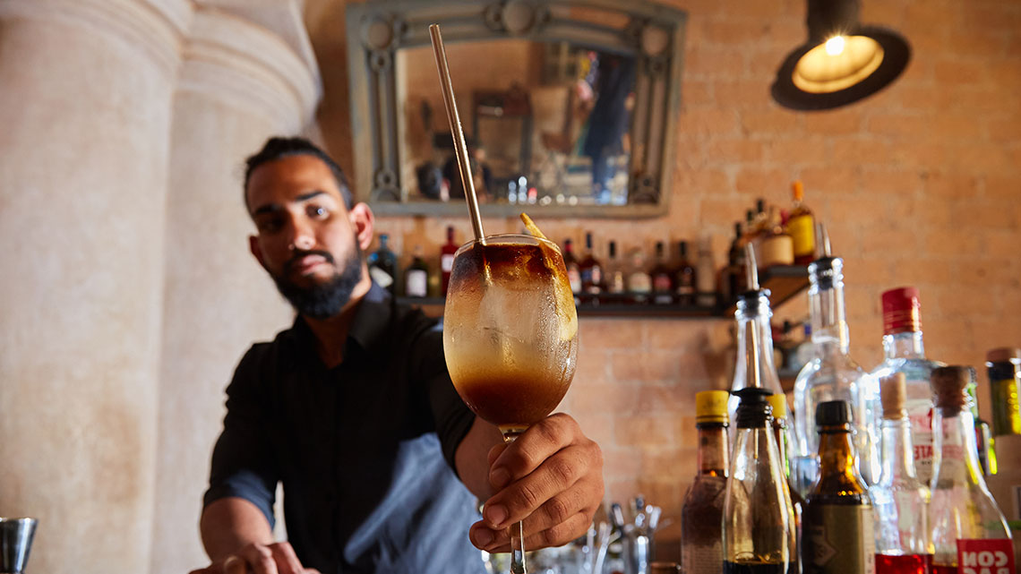 Barman at El Jibaro restaurant in Old Havana offer a cocktail to the photographer